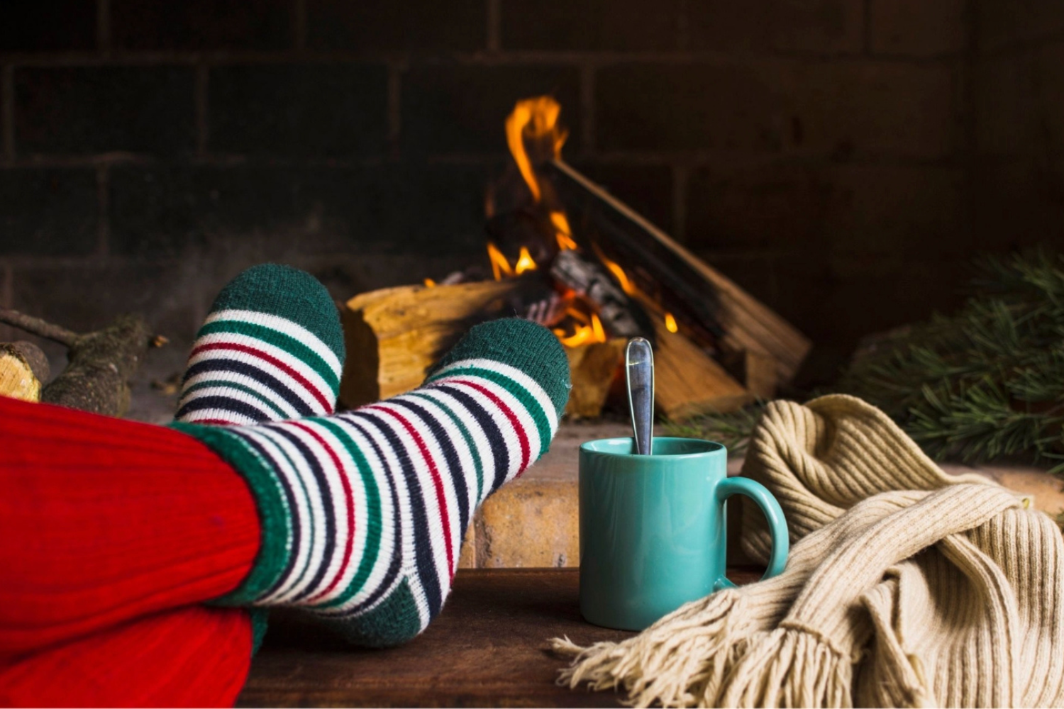 Escena acogedora de Navidad con calcetines a rayas, chimenea, bebida caliente y ambiente festivo