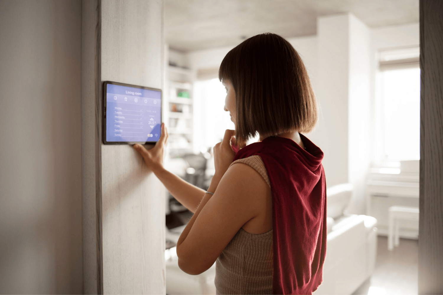 Mujer usando panel de control domótico en tablet para gestionar dispositivos inteligentes del hogar