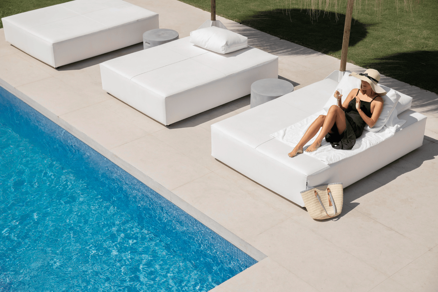 Persona disfrutando del sol en una tumbona junto a la piscina en una casa de vacaciones de lujo.